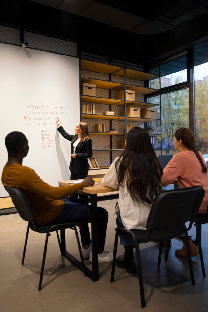 Un professeur écrit sur un tableau des mots d'espagnol devant un groupe d'étudiants adultes
