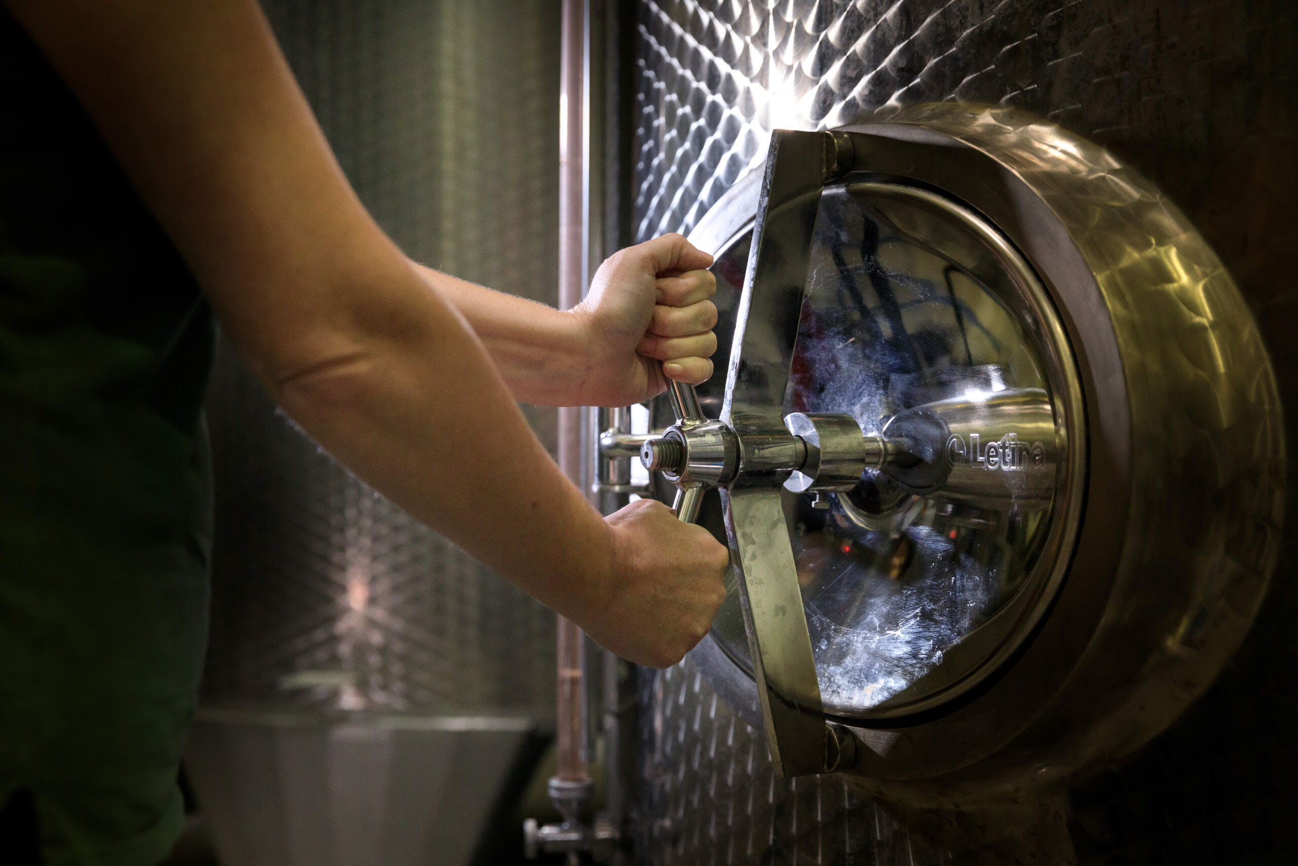 Un caviste ouvre la porte d'une cuve cylindrique en inox